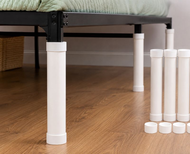 Homemade PVC pipe bed risers installed under a metal bed fram